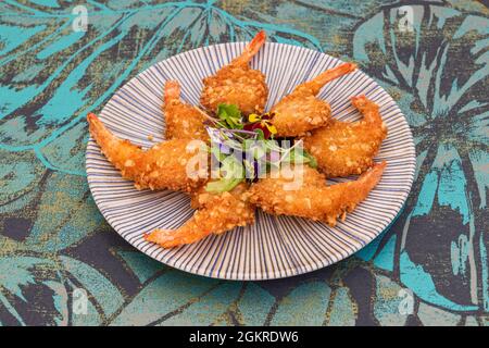 Crevettes panko frites dans l'huile sur une jolie assiette bordée de pousses de légumes Banque D'Images