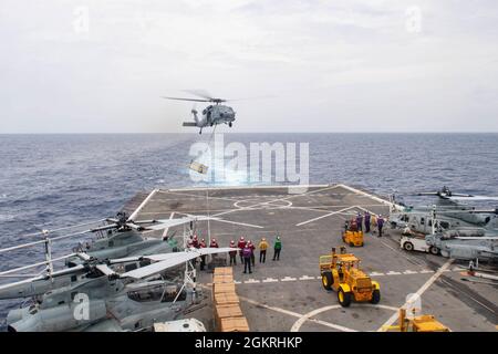 MER DES PHILIPPINES (22 juin 2021) un Faucon de mer MH-60S livre du fret au pont de vol de l'USS New Orleans (LPD 18) lors d'une reconstitution verticale en mer. La Nouvelle-Orléans, qui fait partie du America Amphiobie Ready Group, ainsi que de la 31e Marine Expeditionary Unit, opère dans la zone de responsabilité de la 7e flotte des États-Unis pour améliorer l'interopérabilité avec les alliés et les partenaires et servir de force de réponse prête à l'emploi pour défendre la paix et la stabilité dans la région Indo-Pacifique. Banque D'Images