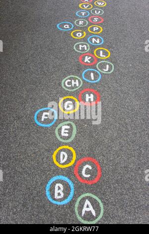 Lettres de l'alphabet en cercles colorés sur une route asphaltée Banque D'Images