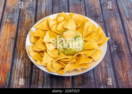 Recette simple pour nachos de maïs mexicain avec guacamole d'avocat sur plaque blanche Banque D'Images