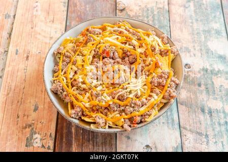 Grand bol de nachos de maïs avec beaucoup de viande hachée, cheddar en sauce, fromage râpé et origan séché Banque D'Images