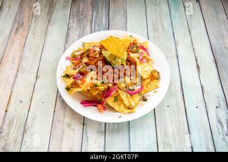 Nachos de maïs mexicain avec guacamole d'avocat, viande de cochinita pibil et tranches de jalapenos sur plaque blanche Banque D'Images