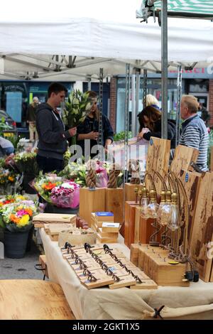 Le client du marché de Louth choisit des fleurs, avec une cabine de travail du bois en premier plan - Louth , Lincolnshire, Royaume-Uni Banque D'Images