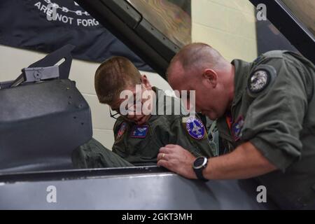 Le lieutenant-colonel Mark Noble de la Garde nationale de l'air des États-Unis, 114e inspecteur général de la Fighter Wing, présente Noah Lamfers, participant à Make-a-Wish, les commandes à l'intérieur d'un simulateur de poste de pilotage F-16 à Joe Foss Field, Dakota du Sud, le 24 juin 2021. Make-A-Wish South Dakota & Montana coordonné avec la 114e aile Fighter pour rendre le souhait des Lamfers de monter dans un F-16 plus vrai. Banque D'Images