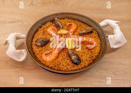 Grande paella de fruits de mer valencienne populaire dans l'été espagnol servi dans une poêle de paella avec de grandes et appétissantes crevettes, des tranches de citron frais et super del Banque D'Images