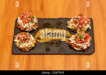 Patacones vénézuéliennes mélangées avec beaucoup de fromage, pico de gallo, sauce tartisable, poulet et canne de porc déchiquetés avec banane mûre sur table en bois Banque D'Images
