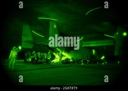 MER DE CHINE ORIENTALE (26 juin 2021) les Marines affectées à la 31e unité expéditionnaire maritime (MEU) chargent un véhicule de reconnaissance sur un MV-22B Osprey lors d'un exercice de raid de nuit sur le pont de vol du navire d'assaut amphibie USS America déployé à l'avant (LHA 6). L'Amérique, navire chef de file du America Amphiobie Ready Group, ainsi que le 31e MEU, opère dans la zone d'opérations de la 7e flotte des États-Unis pour améliorer l'interopérabilité avec les alliés et les partenaires et servir de force de réponse prête à l'emploi pour défendre la paix et la stabilité dans la région Indo-Pacifique. Banque D'Images