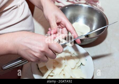 Couper les pommes de terre pour les faire frire . Les femmes préparent la nourriture dans la cuisine Banque D'Images