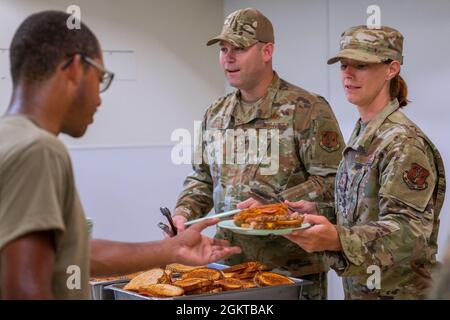 Le Sergent d’état-major Elizabeth Pettek et le Sergent-maître principal David Hill, tous deux membres du 152e Escadron de soutien de la Force, Garde nationale aérienne du Nevada, servent le déjeuner pendant le Camp Paumalau IRT 2021 au Centre d’excellence STEM des éclaireuses d’Hawaï, au Camp Paumalau, à Hawaï, le 28 juin 2021. Les escadrons du génie civil de l'IRT construisent de nouveaux chalets, démolissent d'anciennes structures et embellissent le Camp Paumalau de mai à août 2021, et les escadrons de soutien de la Force rotative fournissent trois repas par jour pour la durée. Une formation de préparation innovante construit des partenariats civilo-militaires mutuellement bénéfiques Banque D'Images