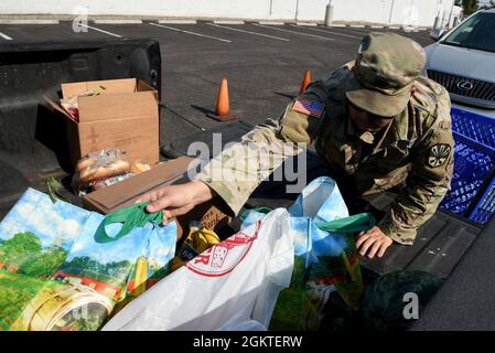 Sergent de la garde nationale de l'Armée de l'Arizona Jacob Lamas, 222 Transportation Company, exploitant de véhicules lourds, livre des produits d'épicerie à un habitant de la région dans une banque alimentaire de Phoenix, le 29 juin 2021. Les citoyens-soldats et les aviateurs de l'Arizona continuent de soutenir les besoins de la communauté pendant l'état d'urgence de la COVID-19. Banque D'Images