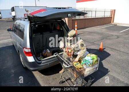 Sergent de la garde nationale de l'Armée de l'Arizona Jacob Lamas, 222 Transportation Company, exploitant de véhicules lourds, livre des produits d'épicerie à un habitant de la région dans une banque alimentaire de Phoenix, le 29 juin 2021. Les citoyens-soldats et les aviateurs de l'Arizona continuent de soutenir les besoins de la communauté pendant l'état d'urgence de la COVID-19. Banque D'Images