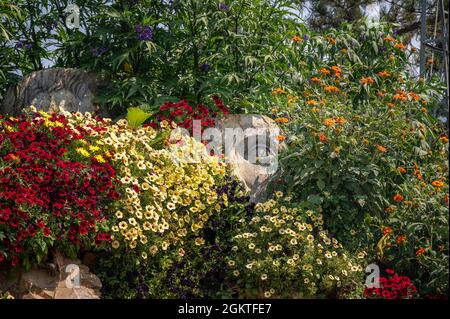 Vue à l'horizon de deux grandes statues dans un jardin a couvert avec plusieurs types de belles fleurs Banque D'Images