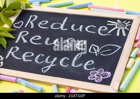 Tableau à craie affiche de recyclage Reuse sur fond jaune avec feuilles vertes et craies Banque D'Images