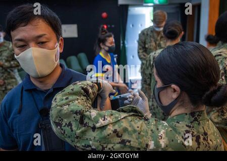 L'Hospitalman Iliana Gonzales, affecté à l'unité NBU (Naval Beach Unit) 7, administre un vaccin COVID-19 à un employé local affecté à l'installation de réparation de navires de la marine américaine et au détachement du Centre régional de maintenance du Japon, au cours de la distribution des vaccins au commandant des activités de la flotte, au théâtre Shosebo's Showboat Theatre le 30 juin 2021. Avec l'autorisation du gouvernement du Japon, le CFAS a commencé à administrer des vaccins aux employés du MLC, de l'IHA et de MC en juin 23. Banque D'Images