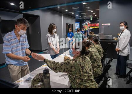 Les marins affectés à la clinique de santé de la branche de Yokosuka de l’Hôpital naval des États-Unis Sasebo aident les employés japonais du contrat-cadre de travail (MLC), de l’entente d’embauche indirecte (IHA) et du contrat de Mariner (MC) avant de recevoir la vaccination Moderna COVID-19 pendant la distribution du vaccin au théâtre Showboat du commandant des activités de la flotte Sasebo (CFAS) le 30 juin 2021. Avec l'autorisation du gouvernement du Japon, le CFAS a commencé à administrer des vaccins aux employés du MLC, de l'IHA et de MC employés sur la base en juin 23. Banque D'Images