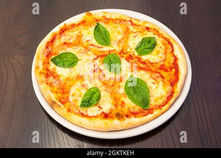 Pizza italienne typique avec beaucoup de fromage mozzarella, tomates et feuilles de basilic Banque D'Images