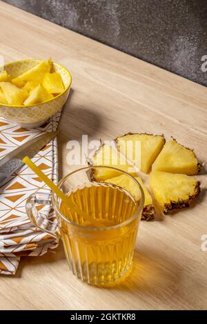 morceaux d'ananas hachés, tissu avec détails triangulaires bruns, jus d'ananas dans une tasse en verre et couteau avec motifs gravés sur la lame Banque D'Images