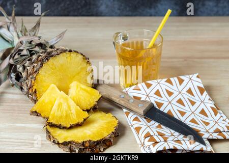 Ananas coupé en deux et morceaux d'ananas sur le dessus, jus d'ananas dans un verre et couteau sur un chiffon Banque D'Images