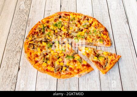 Pizza aux légumes avec champignons, maïs doux et poivre vert avec fromage haché sur une table blanche Banque D'Images