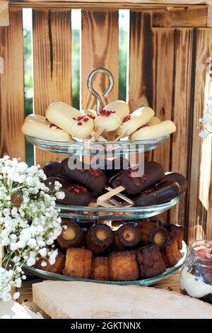 Fragment d'une table de dessert. Gâteau POPS en difficulté et chocolat noir et canules. Gypsophilia sous forme de décoration, fond en bois. Banque D'Images