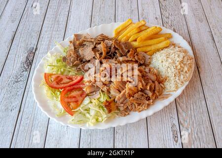 Plateau de Kebab avec poulet rôti et viande d'agneau mélangés garni de riz blanc, de frites, de laitue et de salade de tomates Banque D'Images