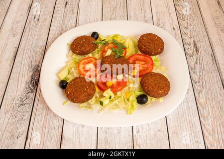 assiette de falafel avec salade de laitue, tomate, oignon blanc, maïs doux, laitue iceberg et olives noires avec concombre servis dans un restaurant kebab Banque D'Images