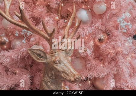 Cerf doré rose fée sur fond d'un arbre de Noël artificiel rose pâle avec diverses boules décoratives roses blanches. Banque D'Images