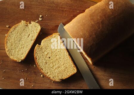 Tranches de pain de blé cuit maison, conservées sur une planche de bois. Banque D'Images