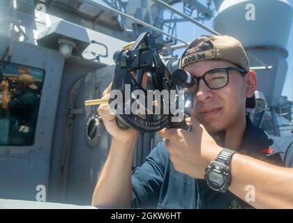 MER DE CHINE ORIENTALE (6 juillet 2021) l'enseigne Daniel Toth utilise un sextant pour mesurer la distance entre le destroyer à missiles guidés de la classe Arleigh Burke USS John S. McCain (DDG 56) et le navire à cargaison sèche de la classe Lewis et Clark USNS Alan Shepard (T-AKE 3) alors qu'ils se préparent à effectuer un réapprovisionnement en mer. McCain est affecté à la Force opérationnelle 71/escadrille de Destroyer (DESRON) 15, la plus grande force DESRON de la Marine et la principale force de surface de la 7e flotte américaine. Banque D'Images