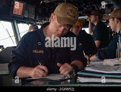 210707-N-LH67-1035 MER DE CHINE DU SUD (7 juillet 2021) le Lt Seth Ballard, officier de guerre anti-sous-marin à bord du destroyer USS Kidd (DDG 100), de la classe Arliegh-burke, prend des notes lors d'un réapprovisionnement en mer. Kidd est déployé en appui au Commandant de la Force opérationnelle (CTF) 71/Escadrier Squadron (DESRON) 15, la plus importante force de surface déployée à l’avant de la Marine et la plus importante force de surface de la 7e flotte américaine. Banque D'Images