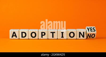 Symbole d'adoption. A transformé un cube en bois et a changé les mots « adoption non » en « adoption oui ». Magnifique arrière-plan orange. Concept d'entreprise et d'adoption, c Banque D'Images