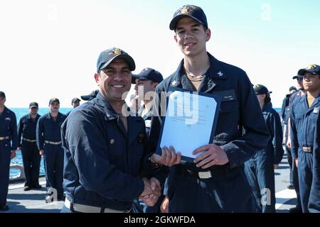 MER NOIRE (9 juillet 2021) Commandant Cmdr. John D. John, à gauche, présente un certificat de nomination au compagnon de Gunner de 2e classe Garrett Holland à bord du destroyer à missiles guidés de classe Arleigh Burke USS Ross (DDG 71) alors qu’il est en cours dans la mer Noire, le 9 juillet 2021. Ross, déployé vers l'avant à Rota, en Espagne, est en patrouille dans la zone d'opérations de la Sixième flotte des États-Unis pour soutenir les alliés et les partenaires régionaux et les intérêts de sécurité nationale des États-Unis en Europe et en Afrique. Banque D'Images