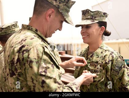 CAMP LEMONNIER, Djibouti (9 juillet 2021)—États-Unis Navy Enginemen 2e classe Katherine L. Penado de Torrance Calif., attachée au Maritime Expeditionary Security Squadron 11 (MSRON-11), Groupe de travail combiné 68.6, basé à Camp Lemonnier, Djibouti, est épinglé par le mécanicien de construction de 1re classe Christopher A. Rodriguez lors d'une cérémonie traditionnelle de repas expéditionnaire (EXW) tenue à la base, le 9 juillet 2021. Au cours de la cérémonie, un casque, signifiant tous les guerriers avant, est passé le long et rempli des éléments suivants, le sable; représentant toutes les plages que nous avons traversées, la terre; la mémoire de Banque D'Images