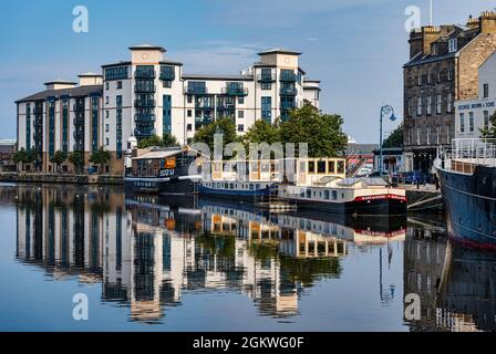 Queen's Quay immeuble moderne au bord de la rivière avec des barges de rivière amarrées reflétées dans l'eau, la rive, l'eau de Leith, Édimbourg, Écosse, ROYAUME-UNI Banque D'Images