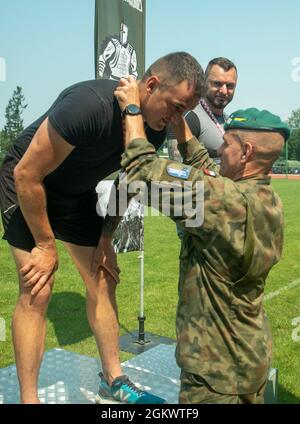 Forces terrestres polonaises, 15e Commandant de brigade mécanisé, Brig. Le général Bogdan Rycerski présente la médaille de la première place du javelin au Lcpl de l'armée britannique. Peter Arnold au Stadion Miejski MOSIR à Giżycko, Pologne 13 juillet 2021. Le groupe de combat Pologne comptait 40 concurrents représentant l'armée des États-Unis, l'armée britannique et les forces terrestres roumaines pour participer à l'épreuve sur piste et sur le terrain, qui comprenait des courses de 100 mètres, 400 mètres, 800 mètres et 4 X 400 mètres ainsi que des compétitions de lancer de javelot, de tir et de saut long. L'événement inaugral multinational de piste et de terrain a eu lieu pour célébrer la 15e mécanisation des Forces terrestres polonaises Banque D'Images