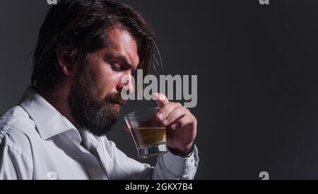 L'homme barbu boit du whisky, de la Brandy ou du cognac. Dégustation et dégustation. Alcool fort. Le sommelier a le goût de la boisson. Banque D'Images