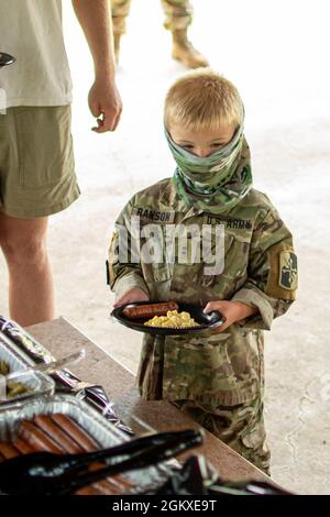 Un fils d’un soldat de la 58e Brigade expéditionnaire du renseignement militaire de la Garde nationale du Maryland attend dans la ligne pour être servi de la nourriture pendant le jour de la famille à fort George G. Meade, Maryland, le 18 juillet 2021. La 58e EMIB a organisé la Journée de la famille pour accueillir les soldats de retour qui sont récemment rentrés chez eux après leur déploiement au Moyen-Orient, ainsi que pour renforcer le moral et construire une camaraderie au sein de l'unité. Banque D'Images