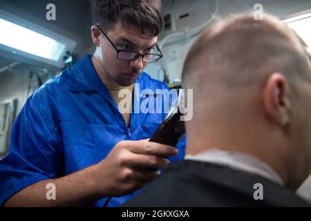 MER DE CHINE DU SUD (19 juillet 2021) le marin spécialisé dans le commerce de détail Brandon Smith, de Toledo, Ohio., coupe les cheveux dans la barbershop à bord du destroyer USS Pinckney (DDG 91) de la classe Arleigh Burke. Pinckney est déployé pour soutenir le commandant de la Force opérationnelle (CTF) 71/Destroyer Squadron (DESRON) 15, la plus importante force de surface déployée à l’avant de la Marine et la plus importante force de surface de la 7e flotte américaine. Banque D'Images