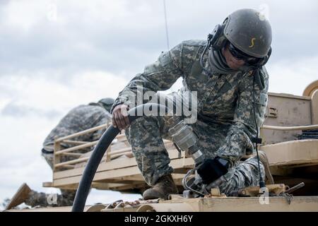 Un étudiant maître Gunner de l'armée américaine, affecté au 3e Escadron, 16e Régiment Calvaire, utilise un tuyau de carburant pour faire le plein d'un réservoir d'Abrams M1A2 SEP V2 à Ware Range, fort Benning, GA., 20 juillet 2021. Ces pétroliers sont formés pour devenir des mater Gunners et être des experts en la matière dans leur domaine. Banque D'Images