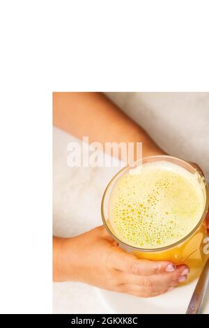 Bébé tient à deux mains un verre de jus d'orange frais. Concept petit déjeuner pour enfants. Enfance et vitamines. Saine alimentation et diète. Bonnes habitudes Banque D'Images