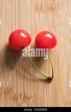 Deux cerises en Tart rouge avec tiges sur fond de bois Banque D'Images