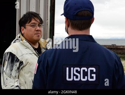 Le sous-officier de 2e classe Craig Bennett (à droite), un technicien en sciences de la mer du Groupe de travail sur la sécurité maritime de la Garde côtière (CSTM), parle avec un employé de l'école James C. Isabell lors d'une inspection d'installation à Teller, en Alaska, le 20 juillet 2021. Dans le cadre de l'inspection, les membres du FSTM discutent des plans d'intervention, examinent la documentation et inspectent l'équipement et les installations de stockage du carburant afin d'assurer la conformité réglementaire. Banque D'Images