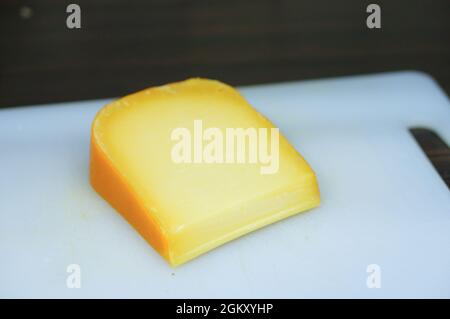 Morceau de vieux fromage Gouda sur une planche à découper bleu clair Banque D'Images