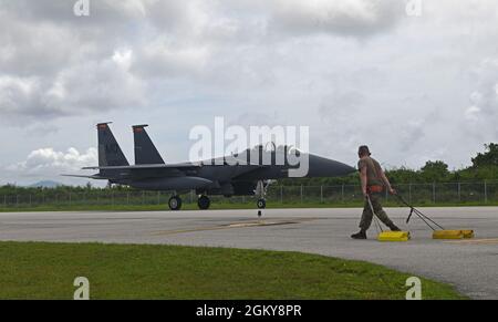 Un F-15E de la US Air Force Strike Eagle de la base aérienne de Mountain Home, Idaho, taxis le long de la ligne aérienne à l'aéroport international de Tinian, Tinian, le 27 juillet 2021, tandis qu'un Airman affecté à la 366e aile Fighter marche le long de cette ligne. Les membres du 366e FW sont arrivés sur Tinian pour une première fois historique afin de soutenir Pacific Iron 2021. Environ 800 aviateurs et 35 avions participent à l’opération d’emploi dynamique des forces aériennes du Pacifique du 11 juillet au 8 août 2021 à Guam et à Tinian pour projeter des forces dans la zone de responsabilité du Commandement Indo-Pacifique des États-Unis à l’appui de la Na de 2018 Banque D'Images