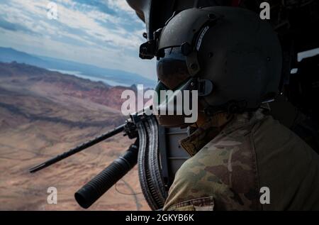 Tech. Sgt. Derrick Schwenk, instructeur avancé du 34e Escadron d'armes, aviateur de missions spéciales, donne des instructions à l'équipage lors de l'entraînement à la manœuvre de combat aérien (ACM), dans un HH-60G Pave Hawk près de la base aérienne de Nellis, Nevada, le 28 juillet 2021. Le but du cours d'instructeur avancé est de former les étudiants à être des experts tactiques dans leur spécialité de combat tout en apprenant l'art de la domination de l'espace de combat. Banque D'Images