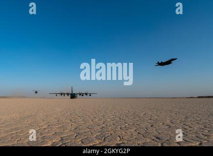 Un hélicoptère Pave Hawk HH-60G de la U.S. Air Force et un aigle F15E Strike survolent un HC-130J combat King II en stationnement au cours d'un exercice le 28 juillet 2021, à un endroit non divulgué quelque part en Asie du Sud-Ouest. Le HC-130J fournit une assistance de récupération ainsi que des capacités de ravitaillement dans les endroits austères. Banque D'Images