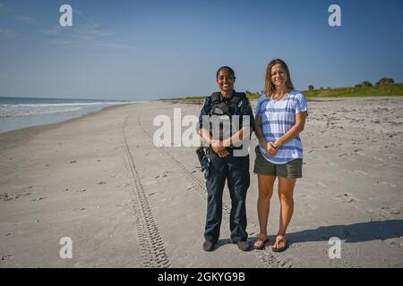 Christy Kalicharan (à gauche), officier de police du 45e Escadron des forces de sécurité et Gretta Lowry (à droite), Cocoa Beach (Floride), résident pose pour une photo de groupe à la base de la Patrick Space Force, en Floride, le 28 juillet 2021. Kalicharan a fourni une aide vitale à Lowry après avoir été mordu par un requin pendant le surf. Banque D'Images