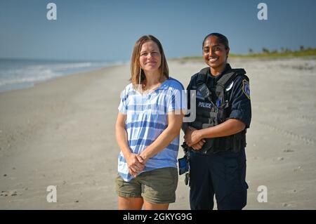 Christy Kalicharan (à droite), officier de police du 45e Escadron des forces de sécurité et Gretta Lowry (à gauche), Cocoa Beach (Floride), résident pose pour une photo de groupe à la base de la Patrick Space Force, en Floride, le 28 juillet 2021. Kalicharan a fourni une aide vitale à Lowry après avoir été mordu par un requin pendant le surf. Banque D'Images