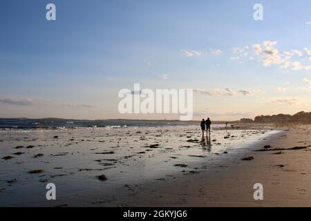 Deux figures en silhouette promenade sur une plage dans le Maine en soirée Banque D'Images