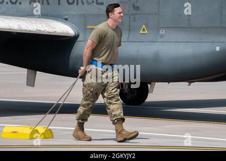 Le principal Airman Riley McAuliffe, spécialiste de l'avionique du 319e Escadron de maintenance d'aéronefs, tire des cales de pneus tandis qu'un Global Hawk EQ-4 est remorqué après son dernier vol à la base aérienne de Grand Forks, N.D., le 29 juillet 2021. Des cales ont été placées autour des pneus de l’EQ-4 pour empêcher tout mouvement tandis que les aviateurs ont salué l’eau pour son dernier vol. Banque D'Images